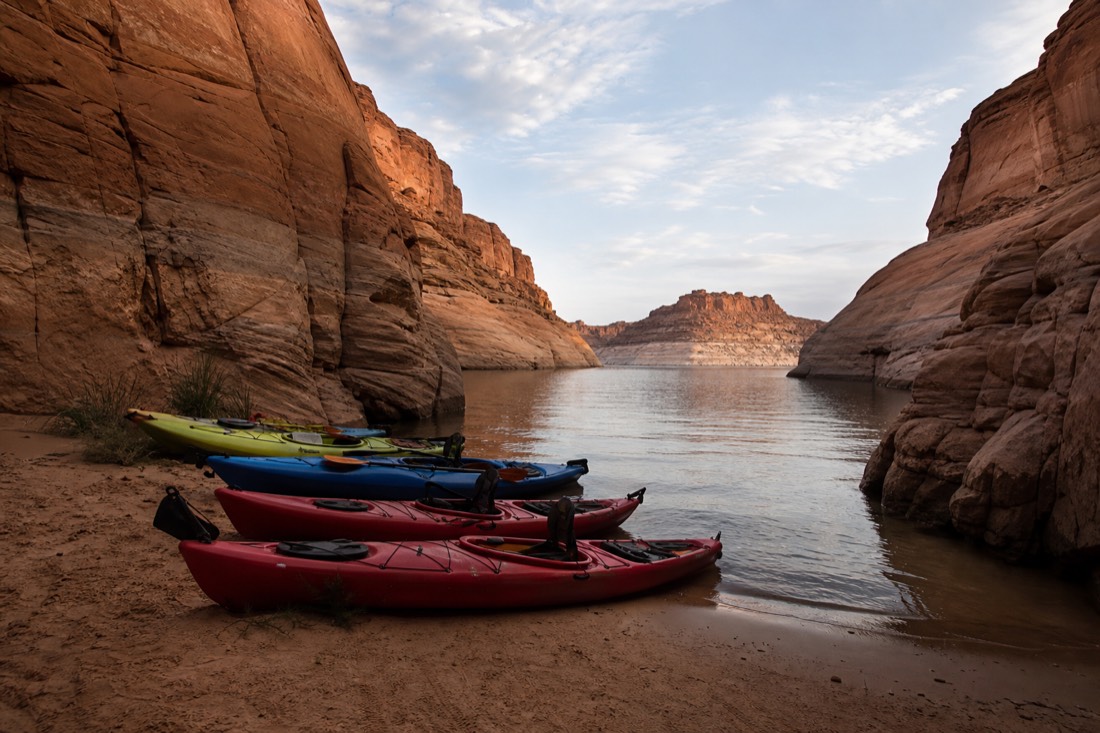 Kayaks pulled onto a sandy shore at the mouth of a canyon arm on Lake Powell