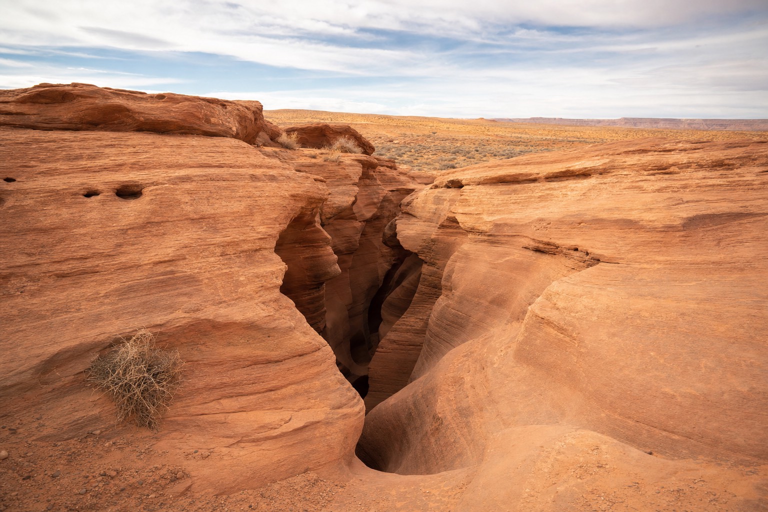 Sandstone slot canyon entrance on Navajo Nation land under an open desert sky near Page, Arizona
