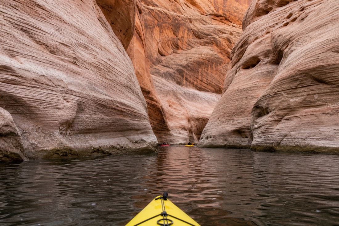 Kayaks entering a narrowing sandstone canyon arm off Lake Powell near Antelope Point