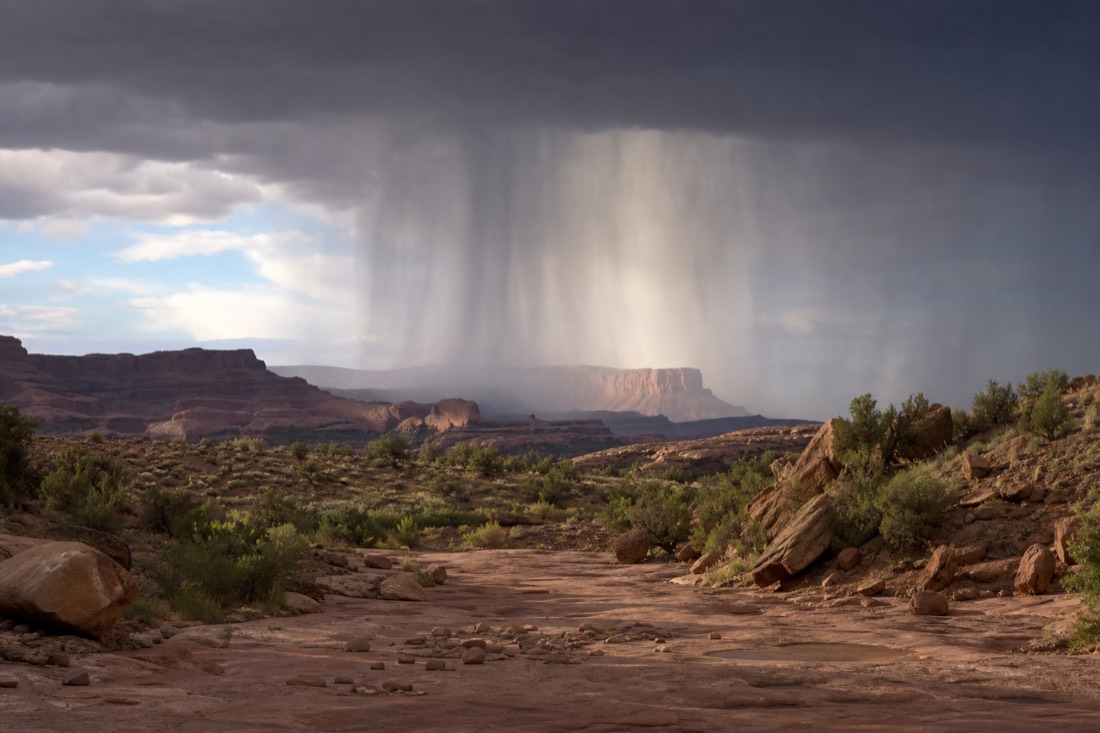 Monsoon rain column falling on distant mesas upstream of a desert wash