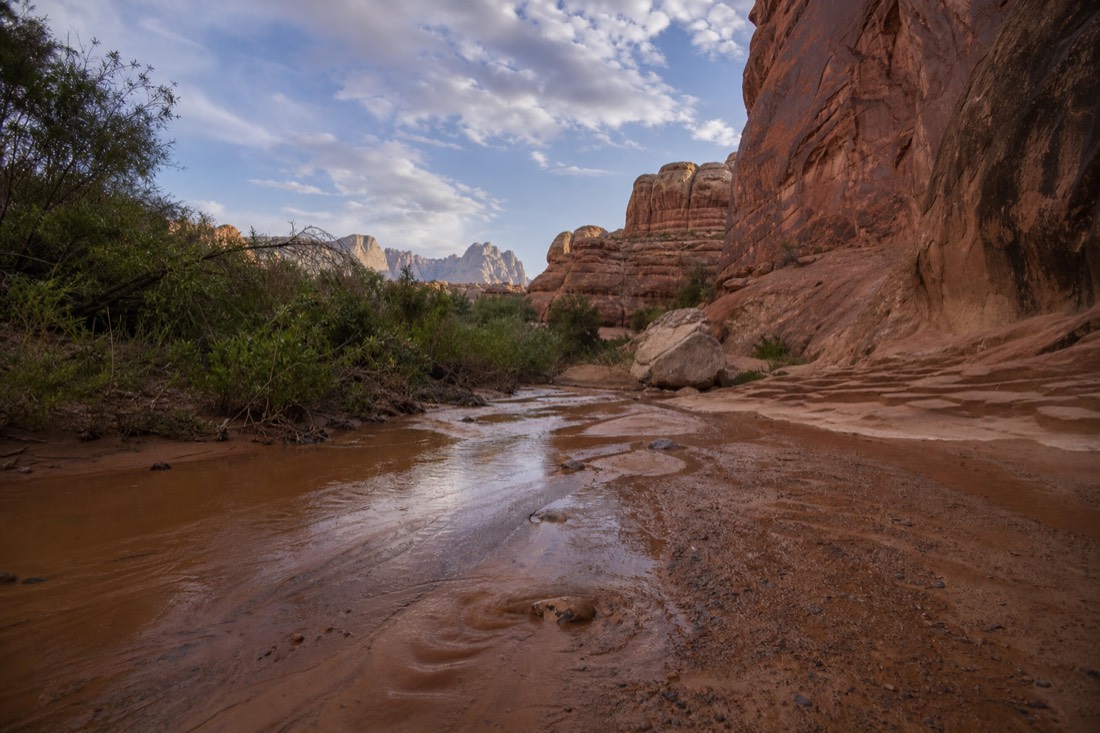 Clearing sky after a desert storm with wet sand in a wash near sandstone cliffs