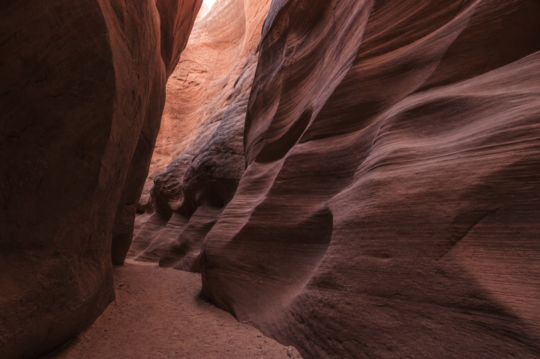 Side by side slot canyon textures: wide dark corridor, sculpted layered waves, and a quiet empty passage
