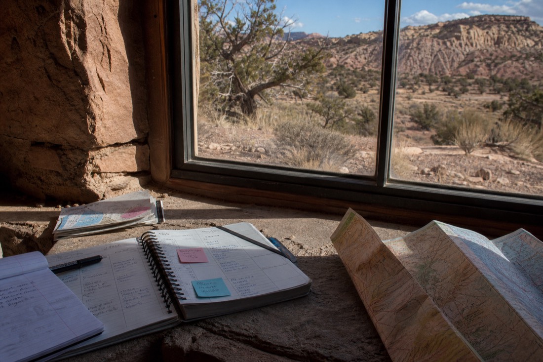 Calendar and travel planning notes beside a sunlit window with desert scenery outside