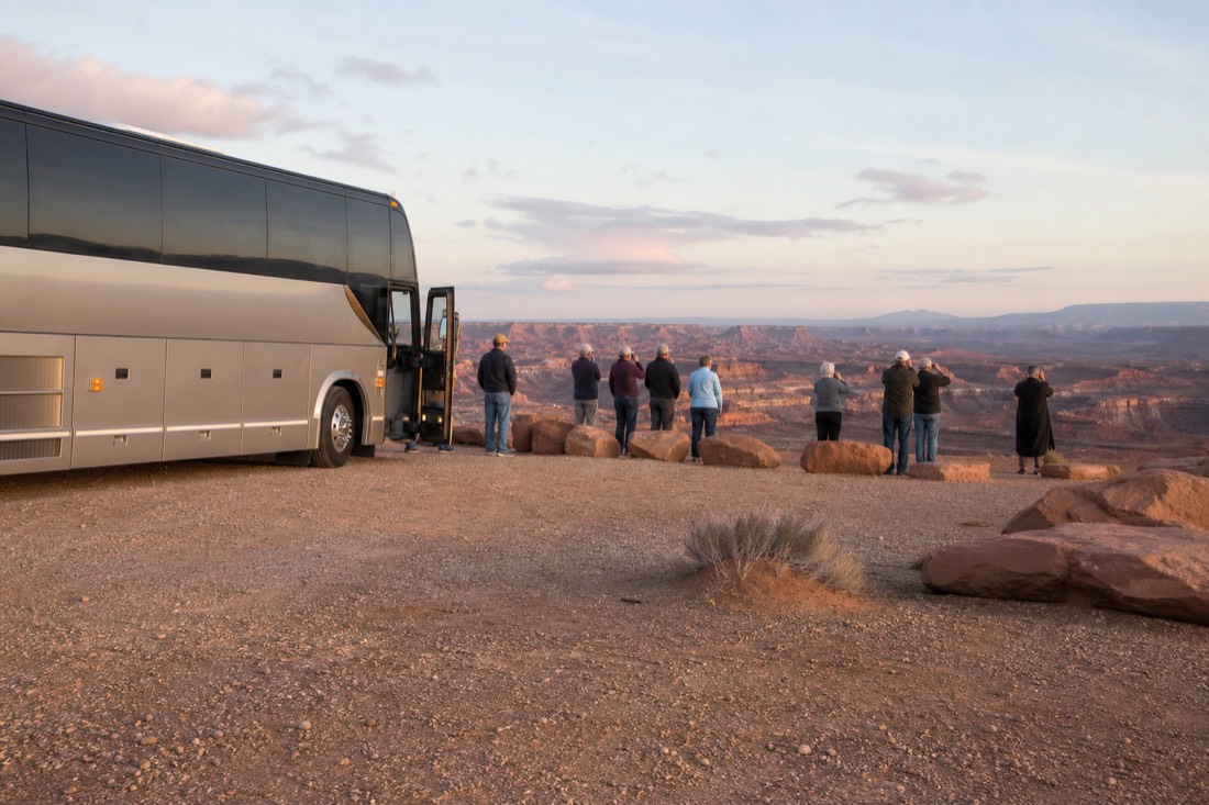 Tour coach parked at a scenic desert overlook with passengers photographing the view