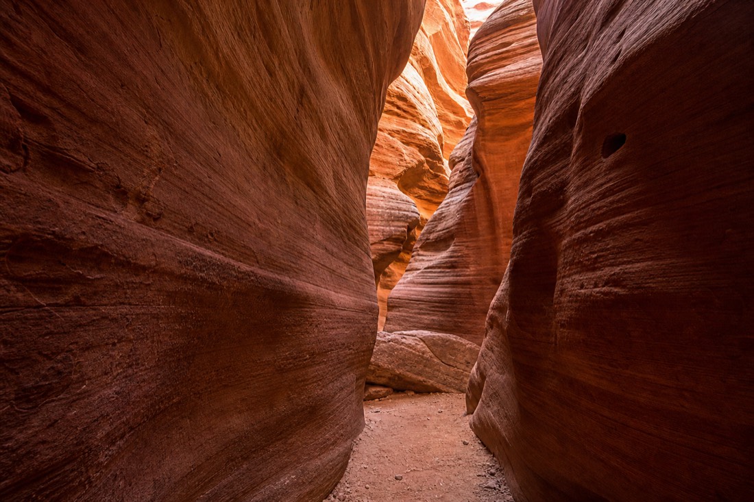 Quiet empty slot canyon passage with layered sandstone glowing in reflected light