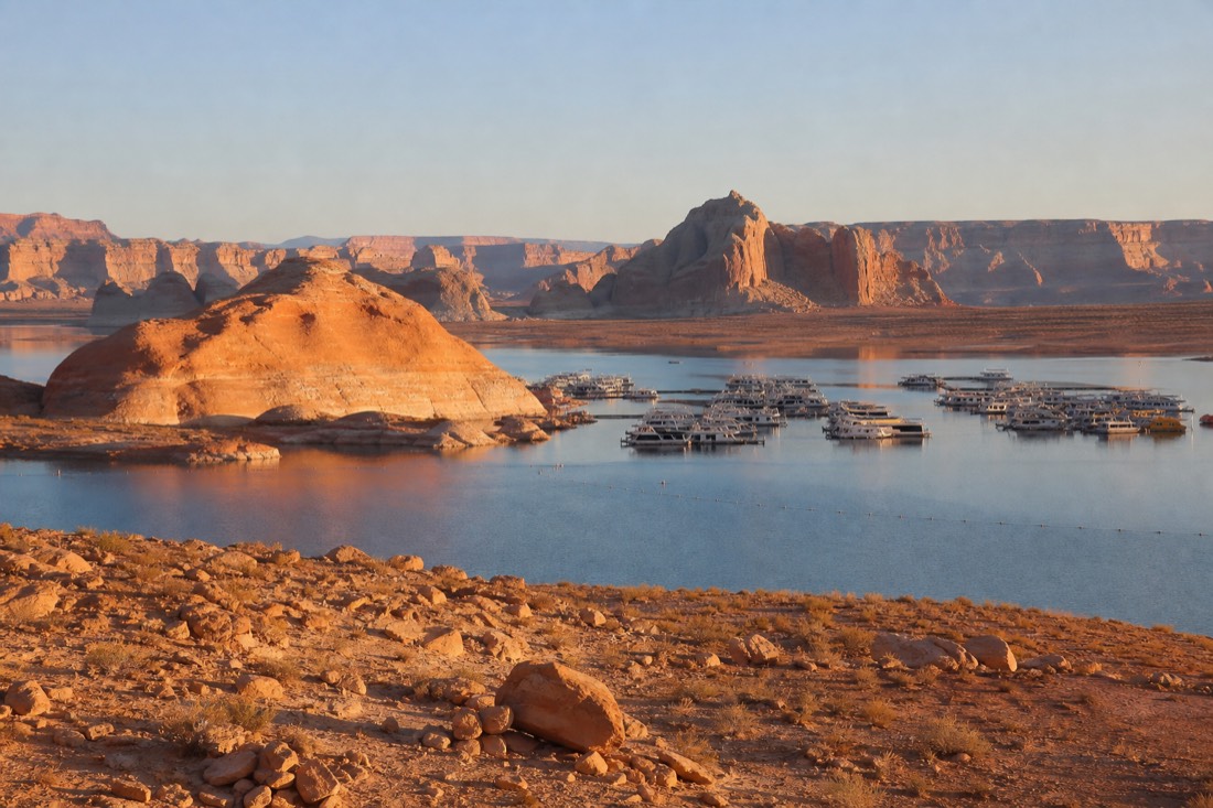 Lake Powell marina bay with houseboats and red rock shoreline at golden hour