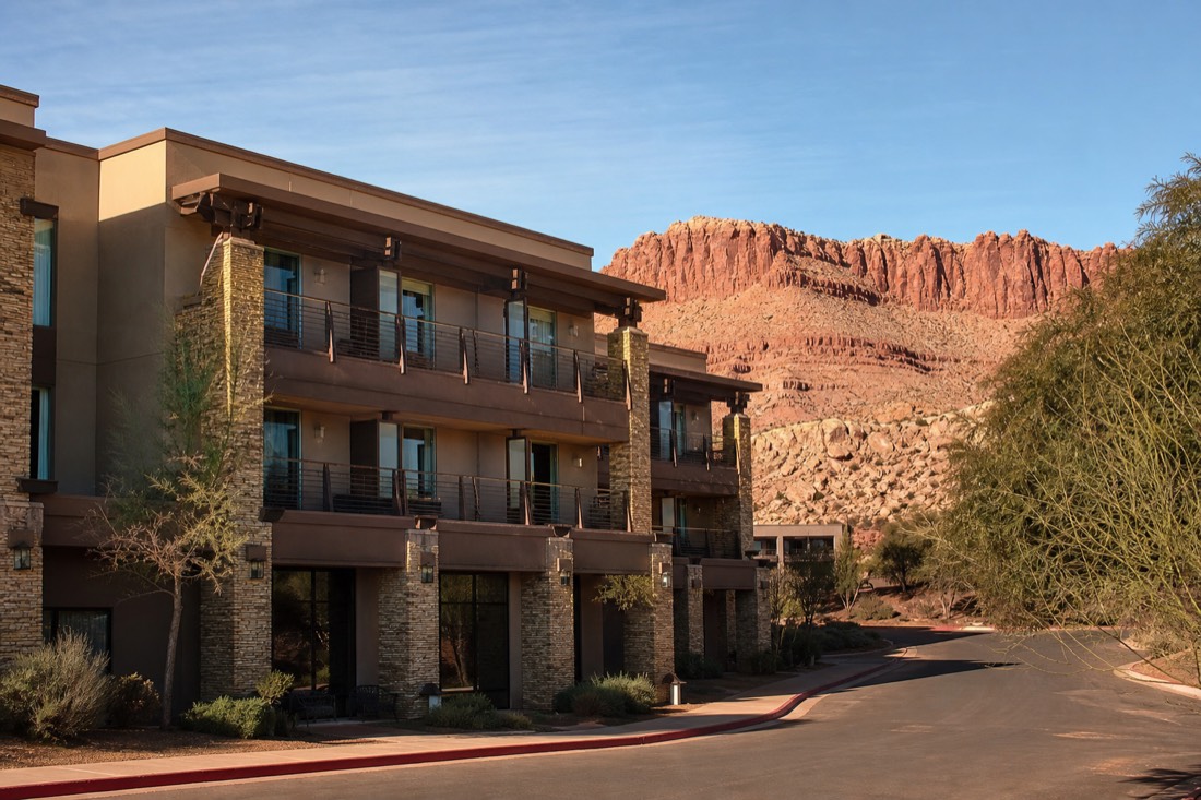 Modern mid-range hotel exterior under a clear desert sky with mesa backdrop