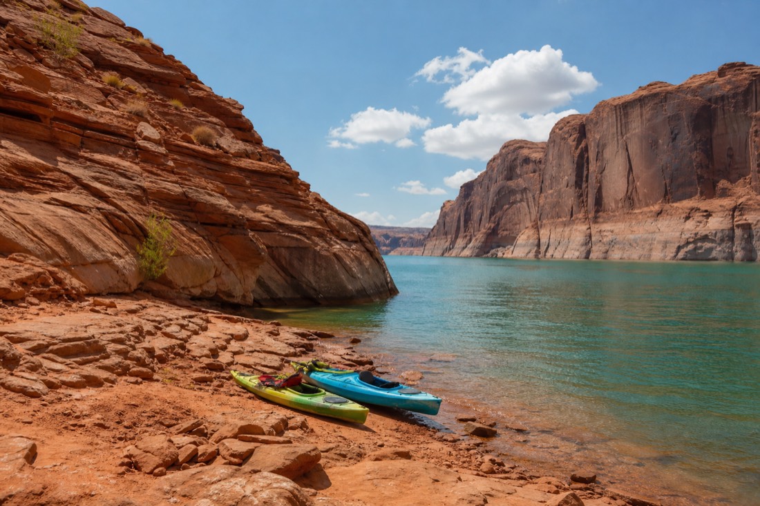 Kayaks on the calm blue water of Lake Powell near the mouth of Antelope Canyon
