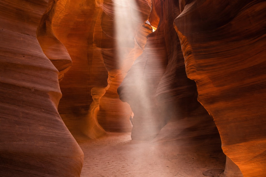 A vertical beam of sunlight hitting the sandy floor of Upper Antelope Canyon